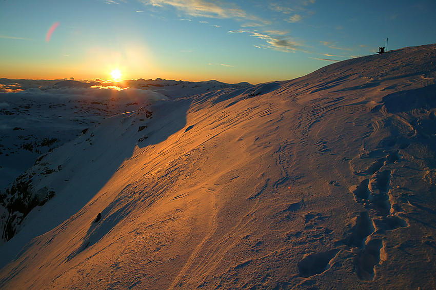 På Gjertvasstinden med utsikt nordøstover mot sola som akkurat har stått opp like ved Galdhøpiggen (2469 moh. - høyeste fjell i horisonten.)