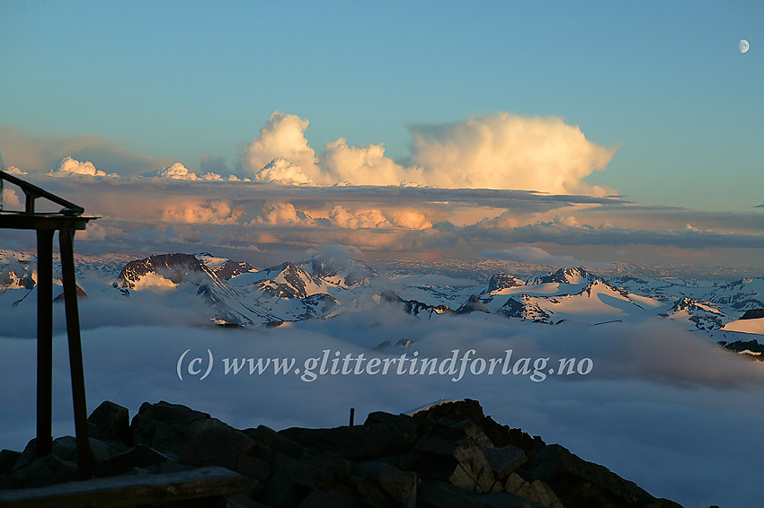 Solnedgang på toppen av Galdhøpiggen en midtsommerkveld mot sør. Visbreatinden, Skarddalstinden, Rauddalseggje og Mjølkedalstinden er blant de mange tindene som bader i kveldssol.