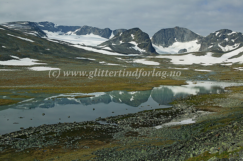 I Trollsteinkvelven der Grotbreahesten (2018 moh.) og Trollstein-Rundhøe (2170 moh.) speiler seg i et lite brevann. I bakgrunnen er det Glittertinden (2464 moh.) som ruver høyest.