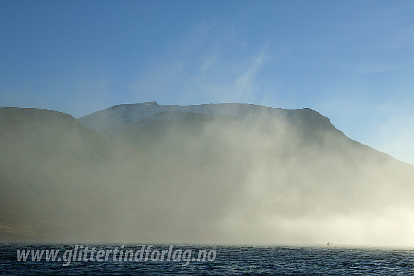 Padling på Bygdin blant morgenskyer på vikende front. Kajakken blir liten mot Galdebergtinden (2075 moh).