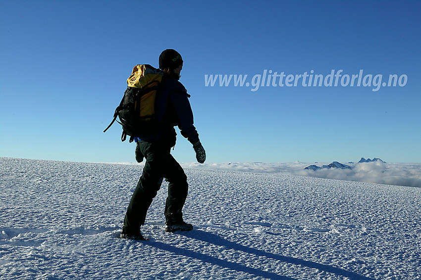 På Slettmarkhøes (2190 moh) snødekte topplatå. I det fjerne stikker bl.a. Hurrunganes topper opp gjennom skylaget.