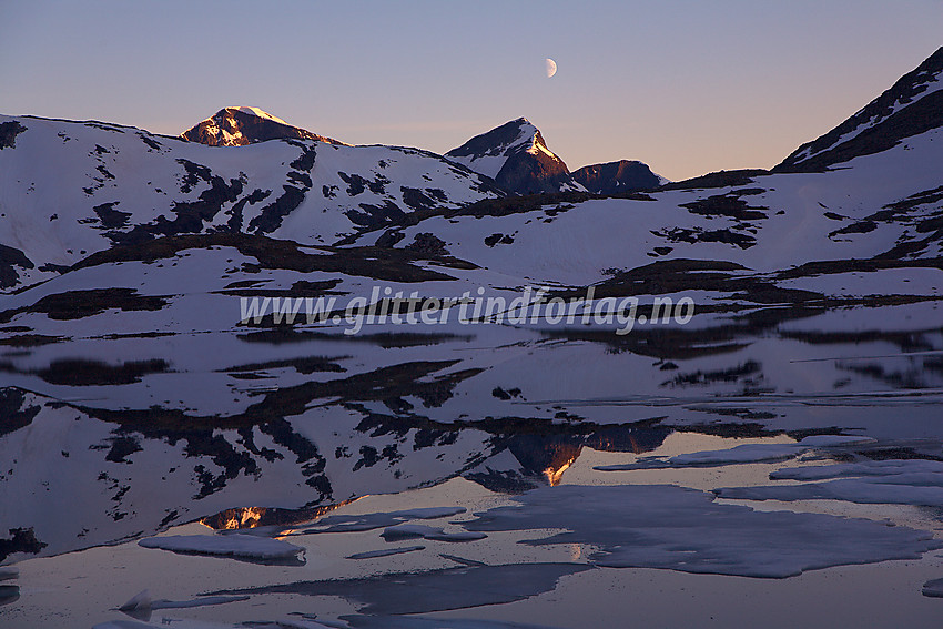 Ved nordbredden av Leirvatnet til solnedgang mot Rauddalstindane (Store, 2157 moh, til venstre og Vestre (2059 moh, til høyre) og en halv full måne.