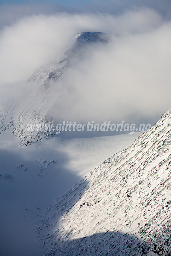 Velsfjelltinden (2157 moh) god innpakket i skyer. Her sett fra Dumhøplatået med telelinse.