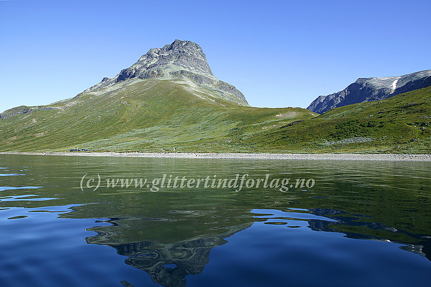 Torfinnstindane (2119 moh) speiler seg i Bygdin. Nede ved stranda ses Torfinnsbu.