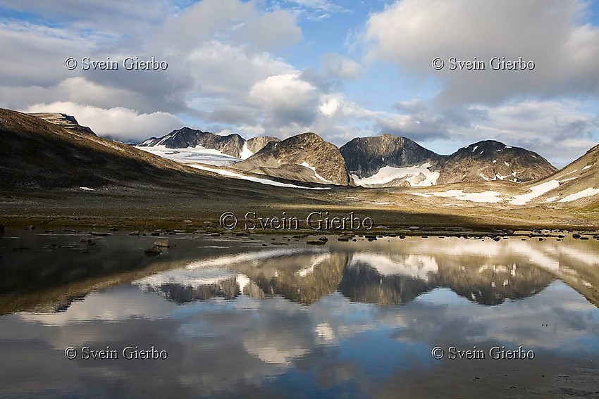 In Trollsteinkvelven valley. Loooking towards Svartholshøe, Trollstein-Rundhøe, Grotbreahesten and Trollsteineggje (right to left) and Grotbrean glacier. Glittertinden, Norways second highest mountain, is obscured by clouds. Jotunheimen National Park. Norway.