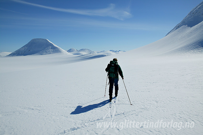 Skiløper på vei østover Holåbrean med kurs mot Austre Holåtinden (2043 moh rett forut). Foten av Midtre Holåtinden (2047 moh) er i ferd med å passeres.