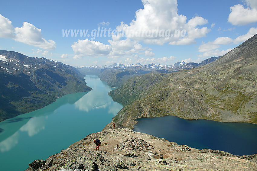 Fjellvandrere på vei opp den siste del av selve Besseggen med Gjende og Bessvatnet i bakgrunnen.