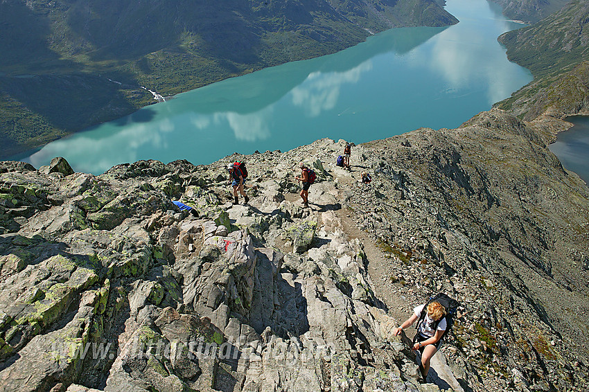 Fjellvandrere på vei opp Besseggen med Gjende i bakgrunnen.