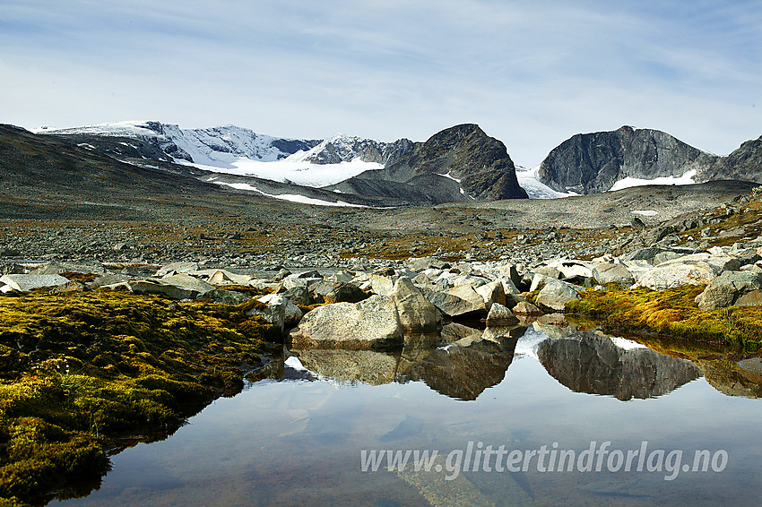 I Trollsteinkvelven med Grotbreahesten (2018 moh) og Trollstein-Rundhøe (2170 moh) som speiler seg i en vannpytt. I bakgrunnen hever Glittertinden seg over alt annet.