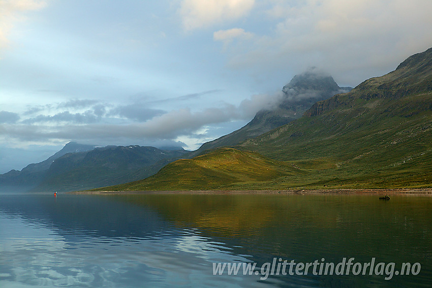 Padling på Bygdin en fredfull sommermorgen. I bakgrunnen duver dovne tåkeskyer rundt toppen på Torfinnstindane (2119 moh).