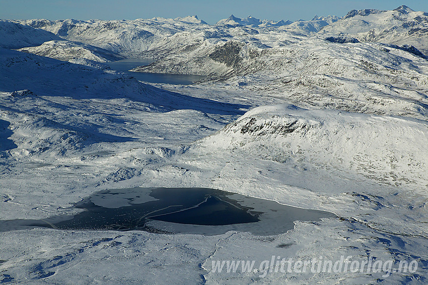 Utsikt fra Bitihorn mot bl.a. Sandhaugen og Skjervebottjernet. Lenger i det fjerne ses Jotunheimens tinderekker fra Galdebergtinden og vestover.