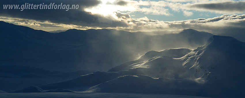 Mefjellet (1386 moh) til høyre med kraftig vind fra vest som slynger snøen dansende ut i lufta.