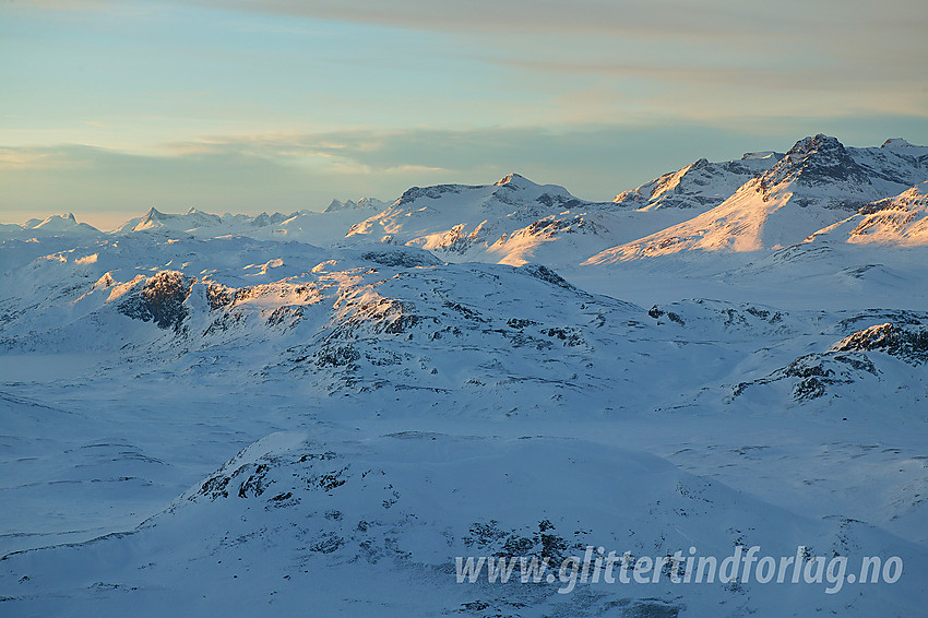 Fra nordryggen på Bitihorn mot Sandhaugen og Marabotthornet i forgrunnen og Jotunheimen med bl.a. Hurrungane, Galdebergtinden og Torfinnstindane i bakgrunnen.