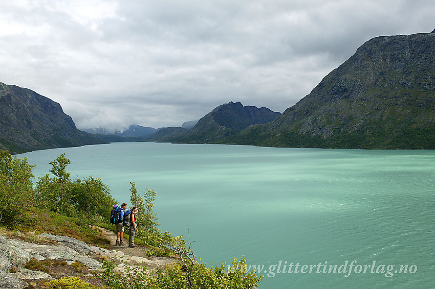 Fjellvandrere på stien mellom Gjendesheim og Memurubu. I bakgrunnen Gjende med Knutshøe i det fjerne.