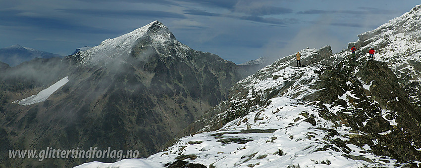 Tre på toppen av Langedalstinden (2206 moh) med Store Knutsholstinden (2341 moh) ruvende i bakgrunnen.