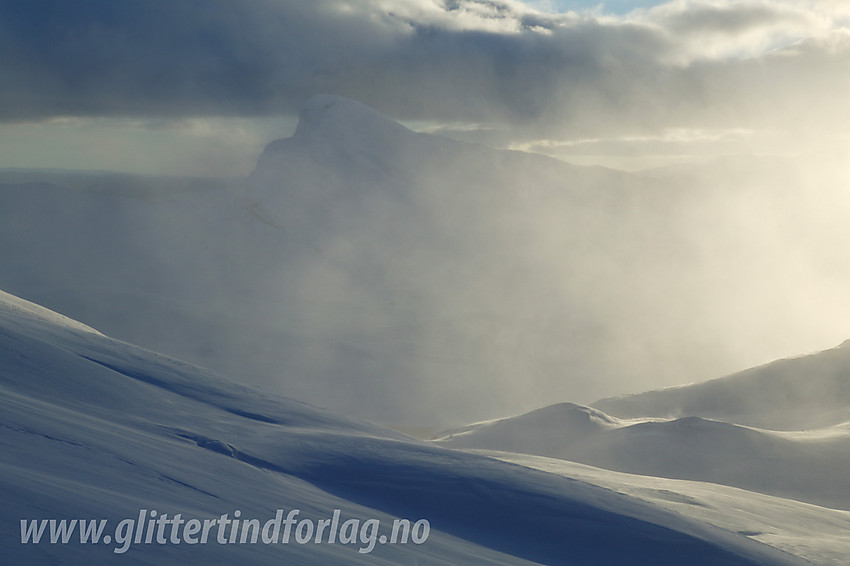 Bitihorn (1607 moh) skimtes gjennom snødrevet som står over Mefjellet. Bildet er tatt fra helningene opp mot Fagerdalshøene.