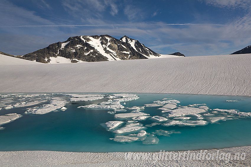 Ved et oppdemt bretjern på Vestre Memurubrean mot Nestsøre (2255 moh) og Store Hellstugutinden (2346 moh). Tjernet ligger tett innunder Hinnåtefjellet på nordsiden.