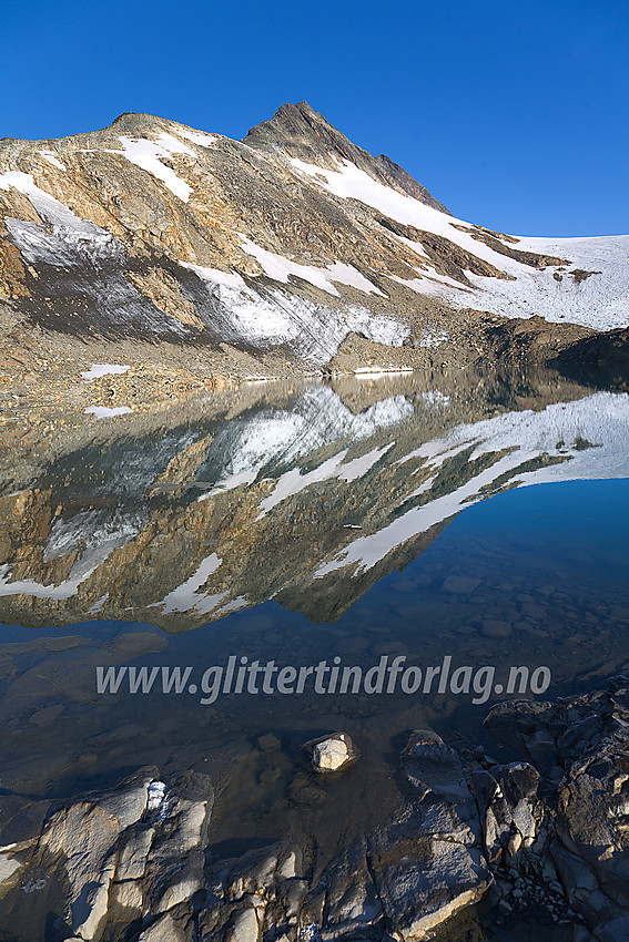 Ved et lite brevann som har smeltet frem ved fronten av Uranosbreen (på litt eldre kart er det tegnet inn isbre her). I bakgrunnen ruver sørryggen på Uranostinden med Uranostinden S2 (2048 moh) som det spisse punktet øverst på eggen. Selve Uranostinden ses såvidt i bakgrunnen.