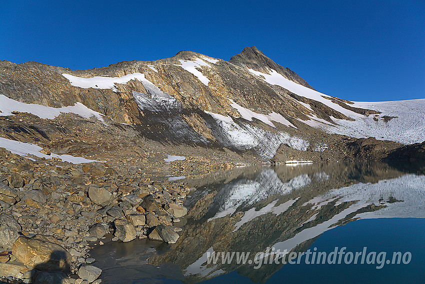 Ved et lite brevann som har smeltet frem ved fronten av Uranosbreen (på litt eldre kart er det tegnet inn isbre her). I bakgrunnen ruver sørryggen på Uranostinden med Uranostinden S2 (2048 moh) som det spisse punktet øverst på eggen. Selve Uranostinden ses såvidt i bakgrunnen.