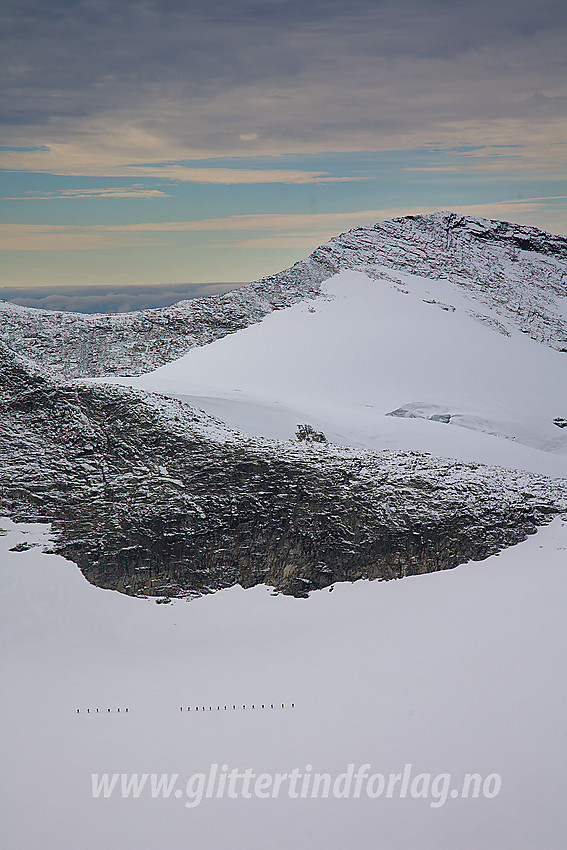 Fra sørøstryggen på Mjølkedalspiggen mot Uraknatten (1958 mo) og Slingsbytinden (2026 moh). Nede på Mjølkedalsbreen er to taulag på tur.