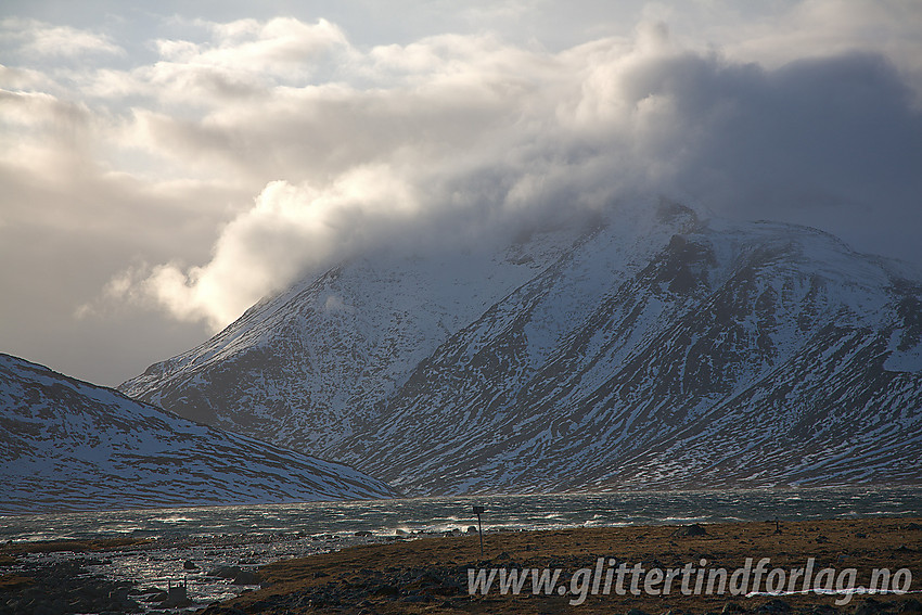 Ved østenden av Bessvatnet med Besshøe i bakgrunnen, dog tildekket av snøfokk og skyer.