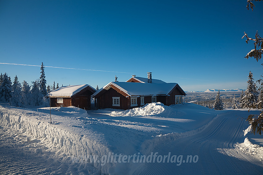 Hytte og skispor i Aurdalsåsen. I bakgrunnen ses fjellene rundt Skogshorn i Hemsedal.