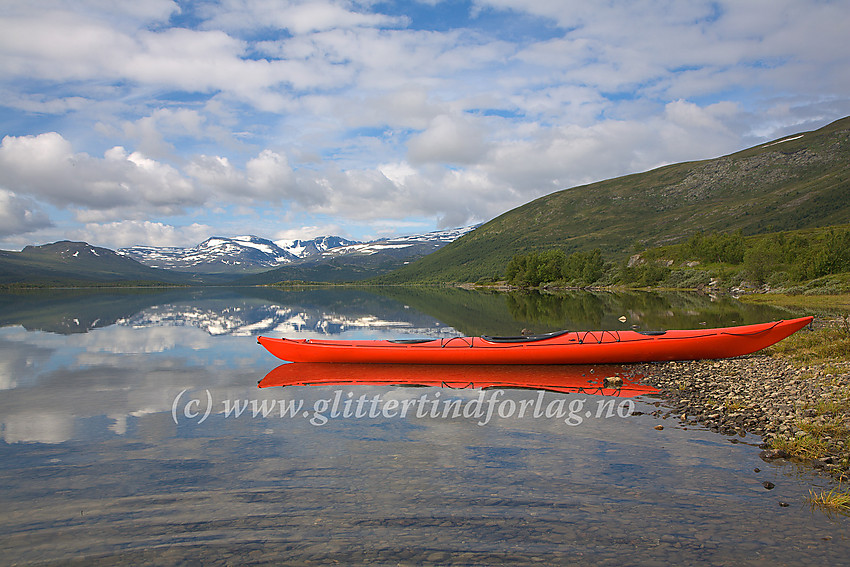 Kajakk på stranda ved Øvre Sjodalsvatnet. I bakgrunnen bl.a. Rasletinden og Munken med Nørdre Brurskardknappen helt til venstre.