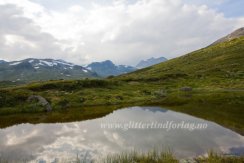 Ved stien mot Surtningssue gjennom Memurudalen passerer man et lite vann. Deler av de vestre Memurutindane kan sees i bakgrunnen til høyre.