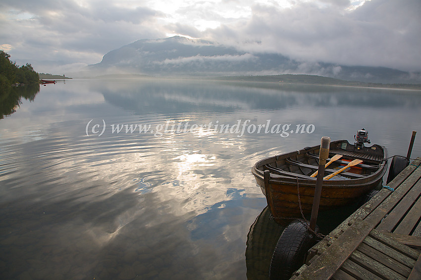 Ved Øvre Sjodalsvatnet en tidlig sommermorgen like nedenfor Bessheim. I bakgrunnen ses Blessomfjellet. Fjellryggen fortsetter mot høyre inn i tåka opp til Sikkilsdalshøe.