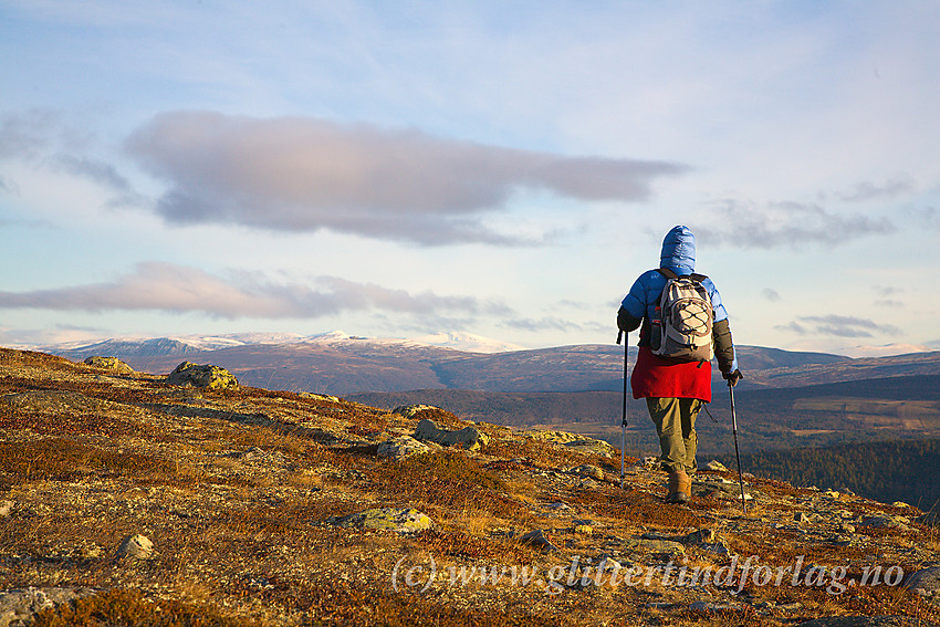 Fjellvandrer på tur på Trollhøemassivet mellom Tesse og Lemonsjøen nordøst i Jotunheimen. I det fjerne i bakgrunnen kvitner Dovrefjell til mot horisonten.