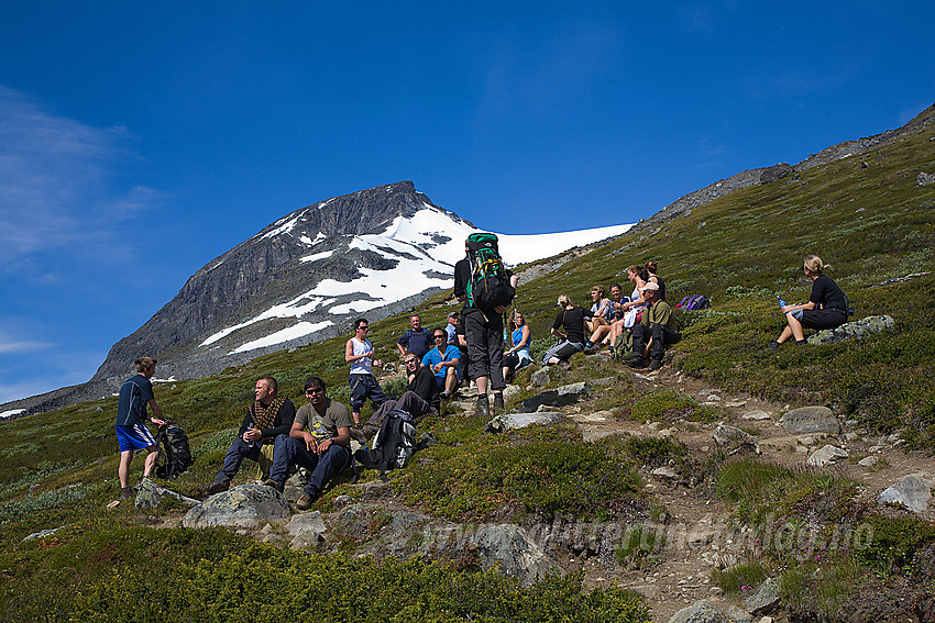 Pause med litt informasjon for gruppe på vei til Svellnosbrean for brevandring. I bakgrunnen skimtes enden på Tverråtindryggen.