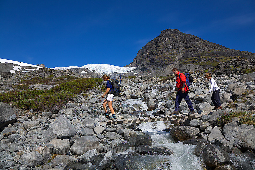 Svellnosbreagrove krysses på liten bro. Breen ses i bakgrunnen.