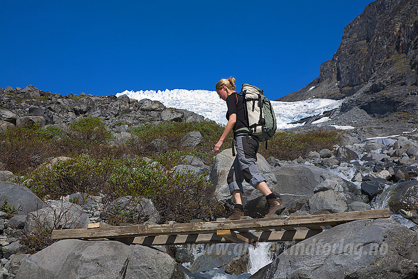 Svellnosbreagrove krysses på liten bro. Breen ses i bakgrunnen.