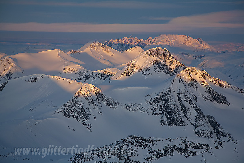 Fra Store Hellstugutinden en aprilmorgen mot tindehavet i vest. Nærmest ses bl.a. Sørvestre Urdadalstinden (2080 moh), Semelholstinden (2147 moh) og Visbreatinden (2234 moh). Videre ses Høgvagltinden, Rauddalstinder og Hurrungane i det fjerne.