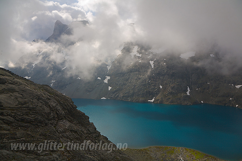 Hjelledalstinden (1989 moh) titter såvidt frem fra tåkeskyene. Nede i Morka-Koldedalen blinker sola i bølgetoppene på det bregrønne Andrevatnet.