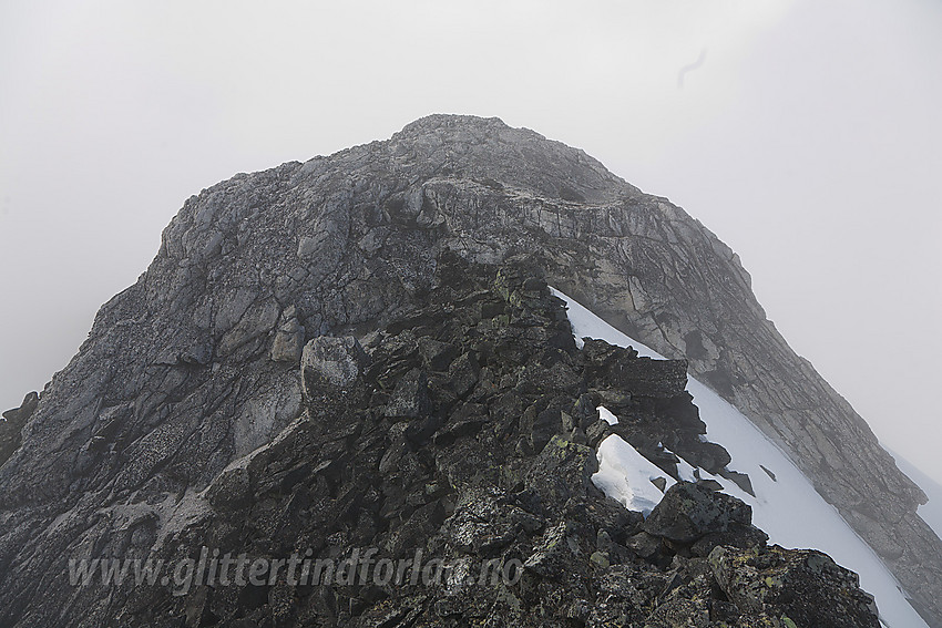 Nørdre Bukkeholstinden (2149 moh) sett fra øst. Der den mørkgrå ryggen når opp til det lysere fjellet er det et kortere parti med klyving grad 2 før man igjen er i enkelt terreng på vei mot toppen.