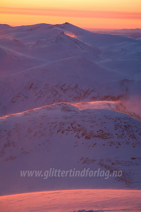 En iskald marsmorgen mot Ryggjehøe (2142 moh) og Nautgardstinden (2258 moh) fra Galdhøpiggen. I forgrunnen ses Keilhaus Topp (2355 moh) og Svellnose (2272 moh). Det ser kanskje idyllisk ut, men en haug med minusgrader i kombinasjon med vinden som fokksnøen avslører, gjorde det hele til en ganske hustrig opplevelse.