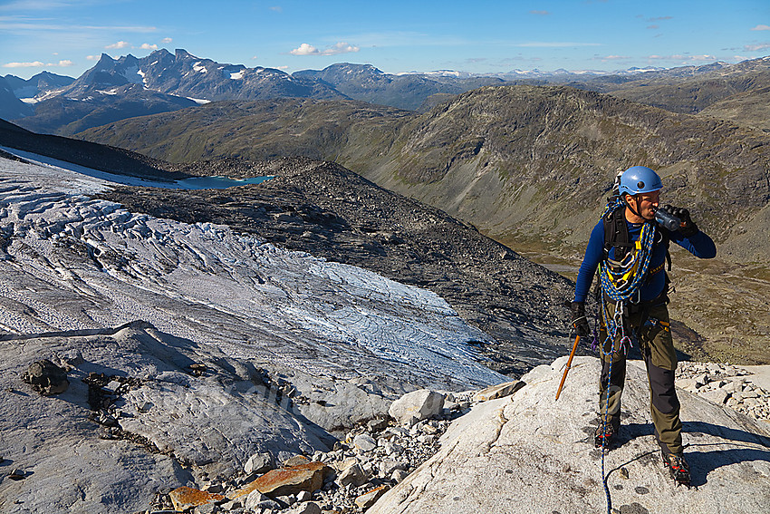 Pause på svaberget i kant av Stølsnosbreen. I bakgrunnen ruver Hurrungane.