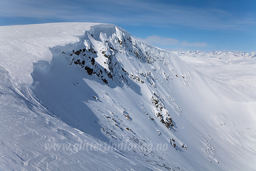 Møsåkerkampen (1740 moh) med snøskavler ut på østsiden. Jotunheimen bak til høyre.