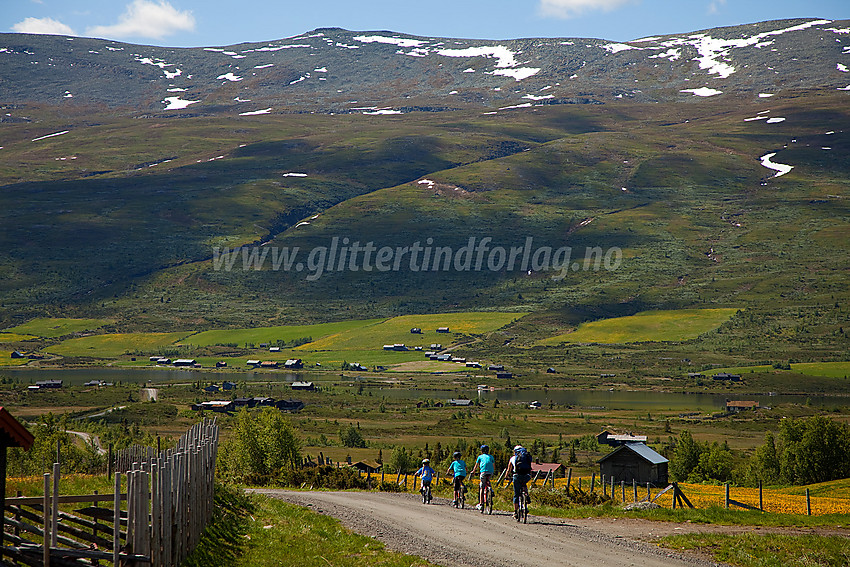 Syklister passerer forbi Syndinstøgo med Gilafjellet i bakgrunnen.