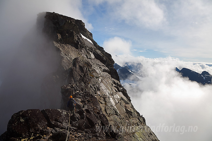 Fra sørligste Austanbotintinden mot den vesle pinakkelen (går nesten i ett med bakgrunnen) og Søre Austanbotntinden (2103 moh). Klamme morgengretne tåkeskyer klamrer seg ennå til fjellsidene mens sola jobber med å gjøre kål på dem.