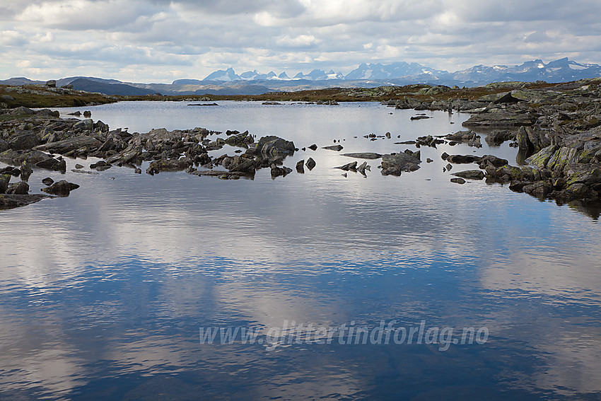 Tjern oppunder Vardhovdtinden. Jotunheimen i bakgrunnen.