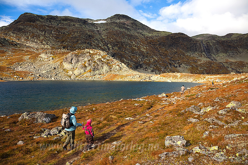 Fjellvandrere på vei inn i Mugnebotten langs det ytterste tjernet med Mugnetinden (1738 moh) i bakgrunnen.