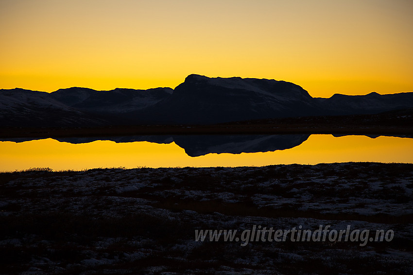 På fjellovergangen mellom Rennefjellet og Syndisfjellet ved Tistruptjernet som bl.a. speiler silhuetten av Grindane.