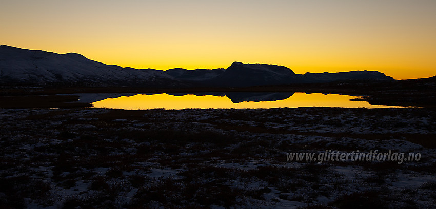 På fjellovergangen mellom Rennefjellet og Syndisfjellet ved Tistruptjernet som bl.a. speiler silhuetten av Grindane.