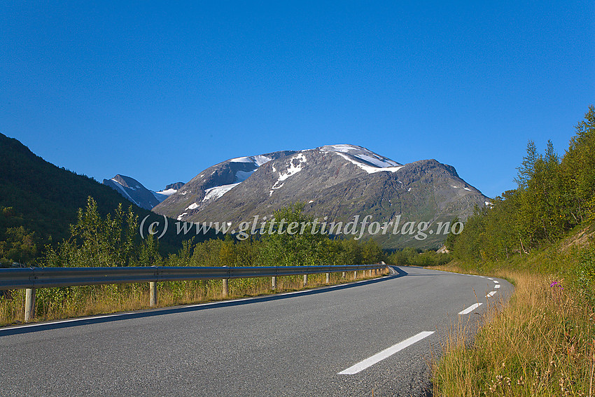 Sommermorgen i Leirdalen ved riksvei 55, like nedenfor avkjøringen mot Leirvassbu. I bakgrunnen dominerer Loftet (2170 moh.) med Veslloftet som et fremspring til høyre. Skagsnebb (2003 moh.) ses langer bak til venstre.