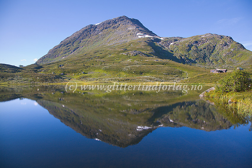 Idyllisk morgenstemning ved Øvre Halsatjønne, rett ved riksvei 55 nær Jotunheimen Fjellstue, med Veslloftet som speiler seg i vannet.