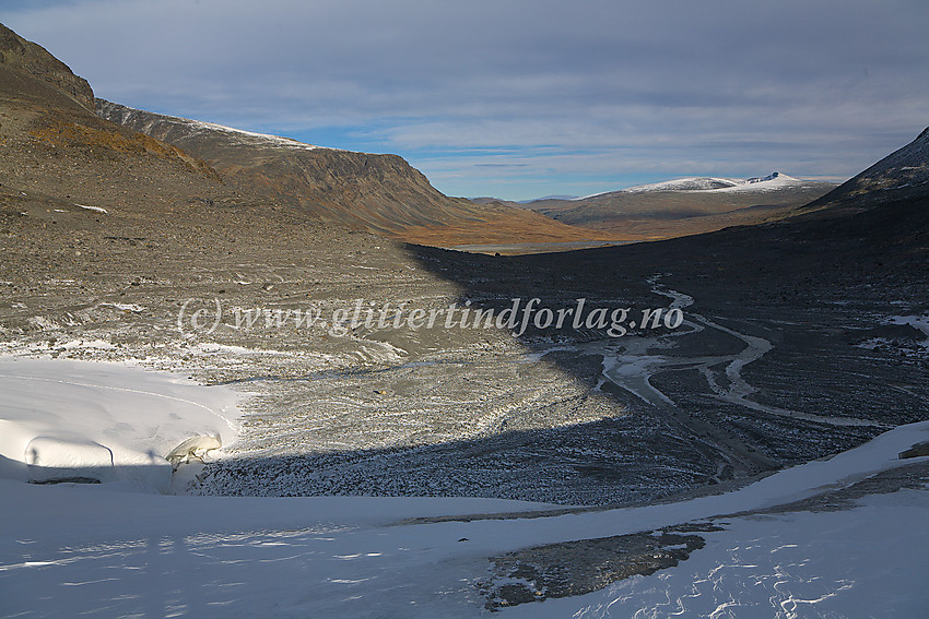 På nedre del av Veobrean, like ovenfor fronten mot morenelandskapet nedenfor og videre mot Veodalen. I det fjerner kvitner Nautgardstinden (2258 moh.) til mot himmelranda.