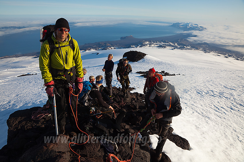 På en liten bergrabb på vei mot toppen. Nunataken 100 meter i bakgrunnen og i det fjerne Sør Jan.  Havtåka stanger mot fjellene fra høyre og det åpner seg et skyfritt belte på andre siden av øya.