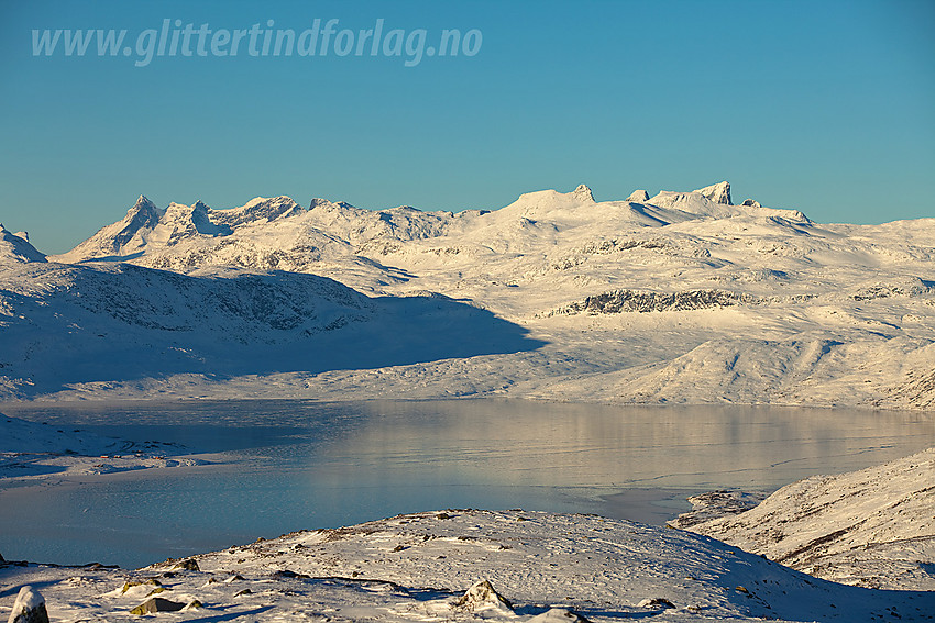 Fra Målegge mot et islagt Tyin. I bakgrunnen hever Hurrungane, Hjelledalstinden og Falketind seg.